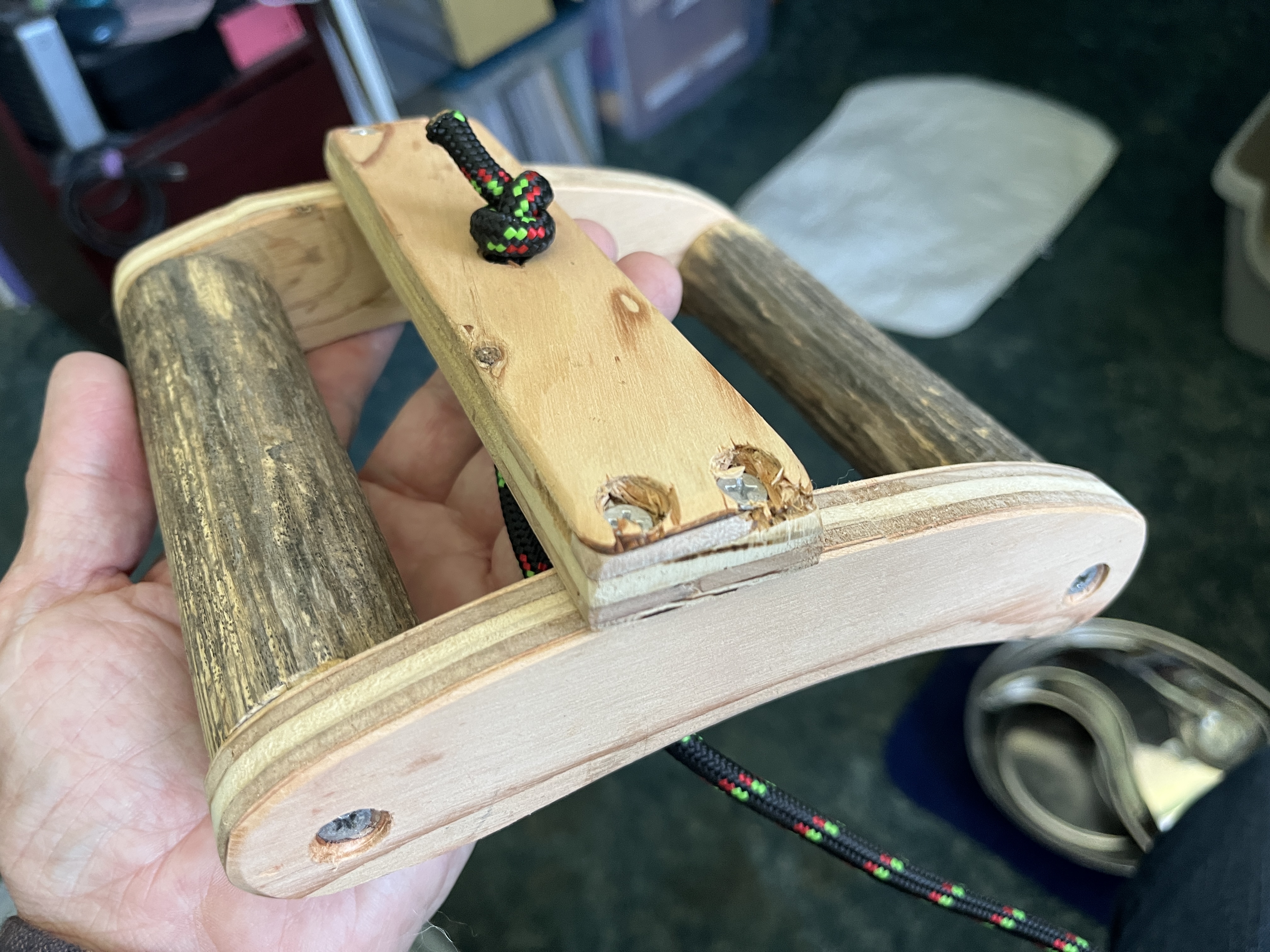 This design mimics the action of some “shave horses,” which pinch the workpiece when the user steps on a lever. It requires only one hole through the workbench for the rope.